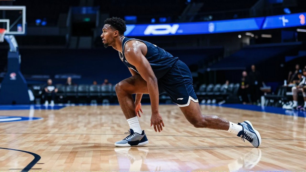 Jugador de baloncesto realizando un cambio de dirección explosivo en una cancha de madera profesional.