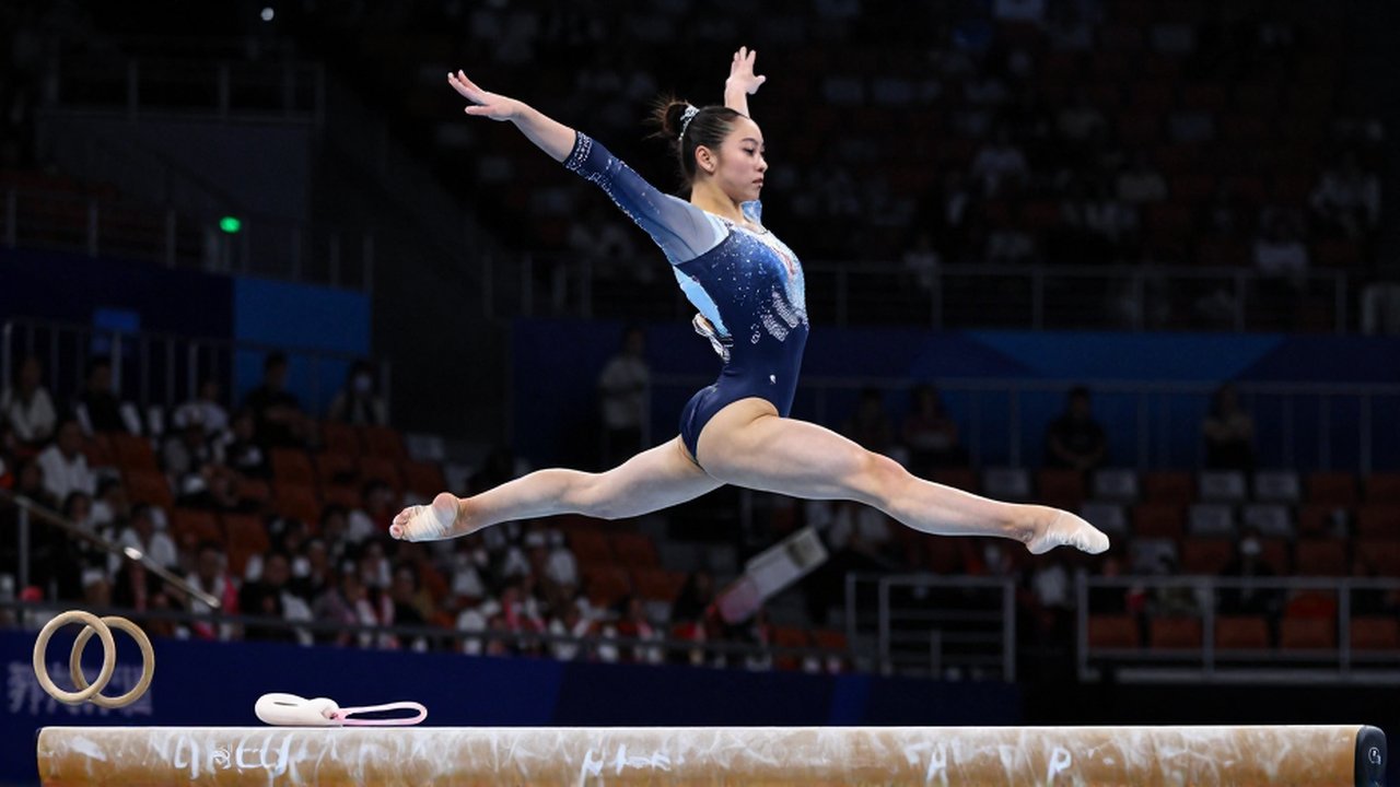 Gimnasta profesional realiza un salto potente sobre una viga de equilibrio en un estadio iluminado.